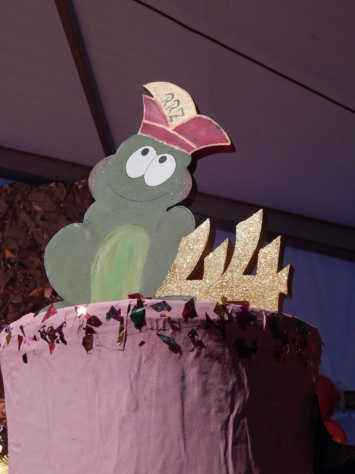 Frosch-Maskottchen mit Narrenkappe und goldener Zahl 44 zum Jubiläum